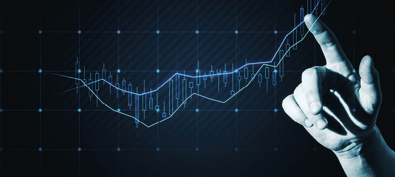 Close up of hand pointing at glowing candlestick forex chart on dark background. Trade, finance and stock concept