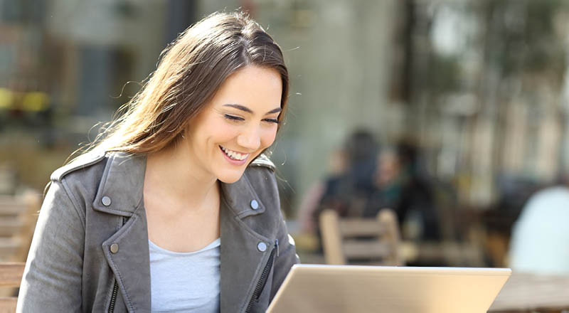 Happy woman typing on laptop on a coffee shop 