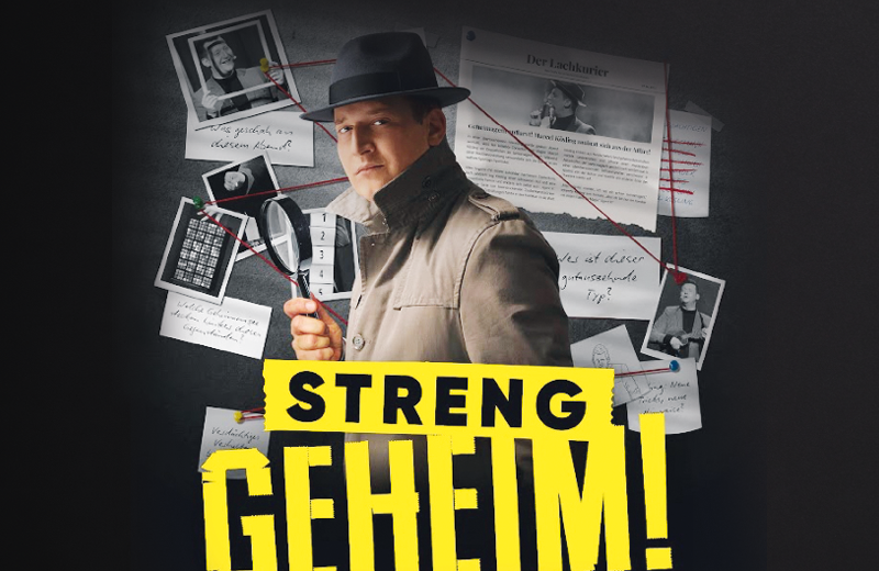 Ein Mann mit Hut und Trenchcoat, die aussehen, als sei er den F nfziger Jahren entsprungen, steht vor einer Wand mit verschiedenen Bildern, Zeitungsausschnitten und handschriftlichen Notizen, die durch einen roten Faden miteinander verbunden sind. In der rechten Hand h lt er eine Lupe. Unten in knallig gelb steht unten streng geheim!“. Foto: GOP Variet -Theater Hannover