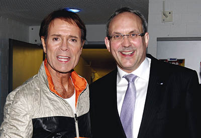 Links im Bild der weltbekannte S nger Cliff Richard in wei -schwarzem B hnen-Outfit und orangem Kragen zusammen mit J rgen Wache Foto: Hannoversche Volksbank