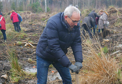 J rgen Wache, vorn, beim graben mit einem Spaten, und weitere Personen auf einer nebligen, herbstlichen Waldlichtung beim setzen junger B ume. Alle haben warme und wetterfeste Kleidung an.  Foto: Hannoversche Volksbank