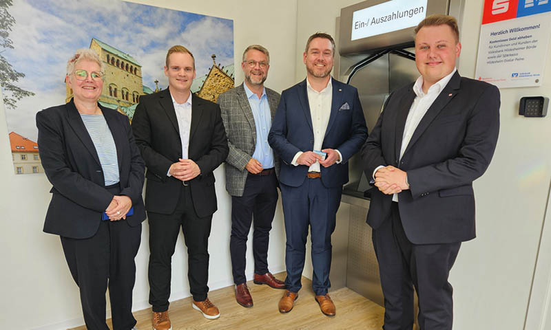 F nf Personen stehen vor einem gro en Foto des Hildesheimer Doms und einem Geldautomaten im gemeinsamen SB-Center in Schellerten der Volksbank Hildesheimer B rde und der Sparkasse Hildesheim. Foto: Hannoversche Volksbank