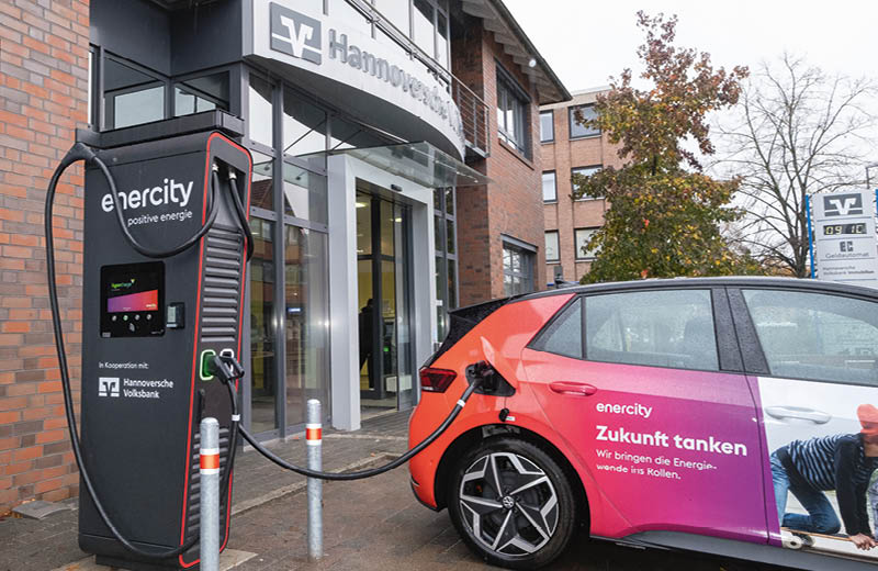 Vor einer Filiale der Hannoverschen Volksbank steht eine Lades ulen von Enercity in Kooperation, mit der Hannoversche Volksbank, an der ein Elektroauto geladen wird. Foto: Tim Scharschmidt