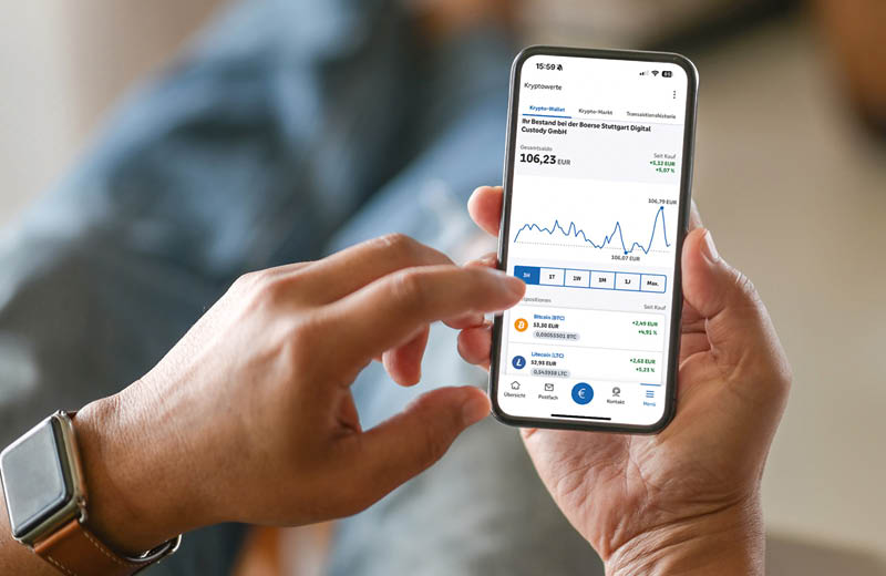 Die rechte Hand h lt ein Smartphone, auf dessen Display man eine Diagrammkurve und verschiedene Zahlen in Euro und Prozent sieht. Der Zeigefinger der linken Hand bedient das Display am Arm befindet sich eine Smartwatch einer bekannten Obstsorte. Foto: BVR