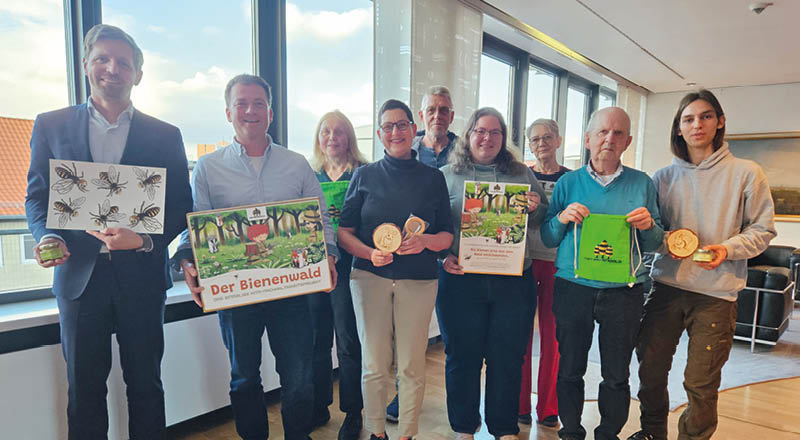In einem Raum vor einer Fensterfront stehen mehrere Personen, die verschiedene Teile der Bienenwaldboxen in der Hand halten. Foto: Hannoversche Volksbank